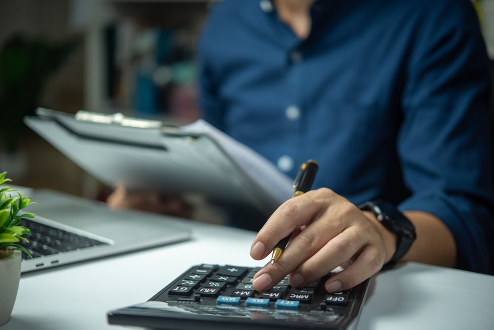 Person calculating bankruptcy filing costs with a calculator and a clipboard