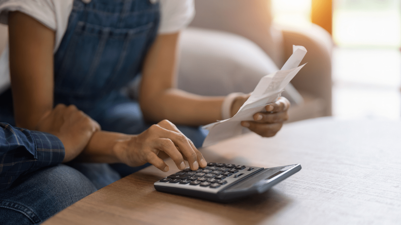 Married woman reviewing paperwork at table with a calculator in hand.