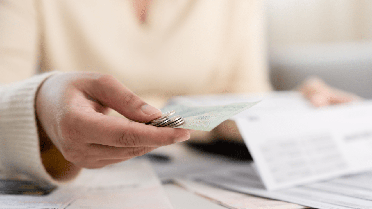 Woman, looking at documents with coins in hand.