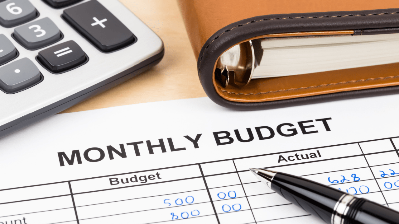 monthly budget with notebook and calculator nearby.