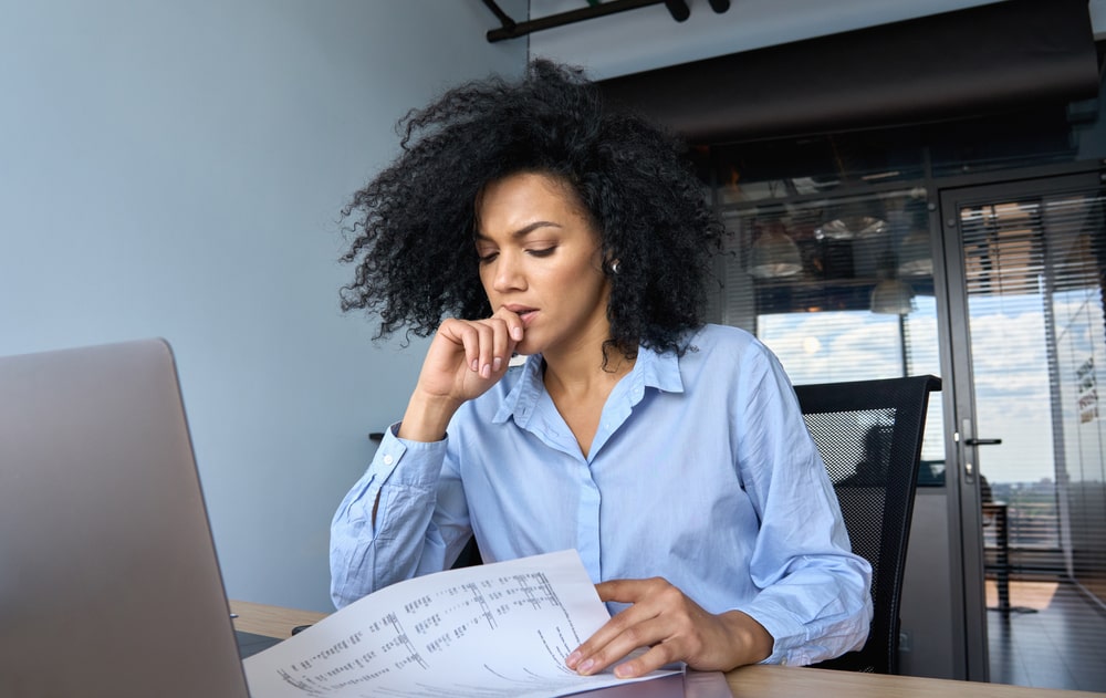 Concerned woman reading financial documents at her office desk