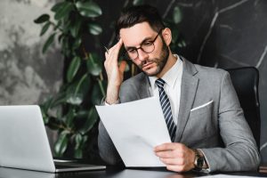 Stressed businessman in a suit reading bankruptcy paperwork at a desk