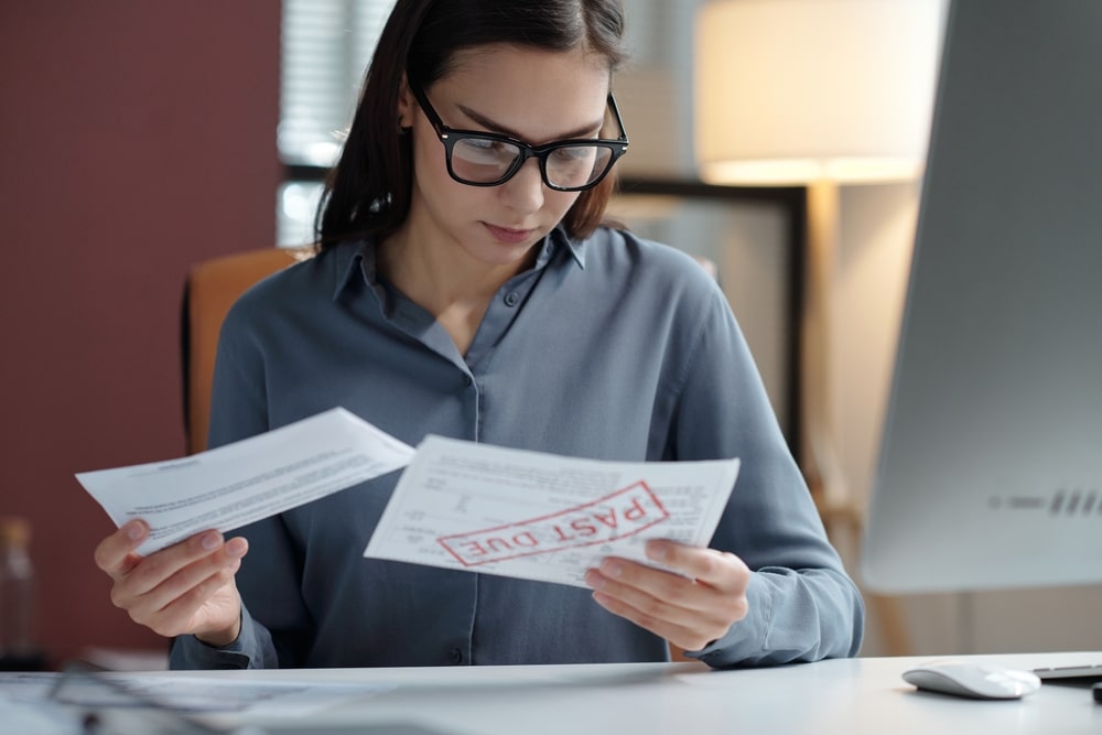 Woman reviewing past due bills and tax documents at her desk