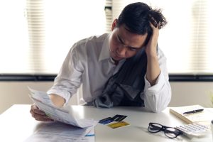 Stressed man reviewing bills and credit cards while considering bankruptcy