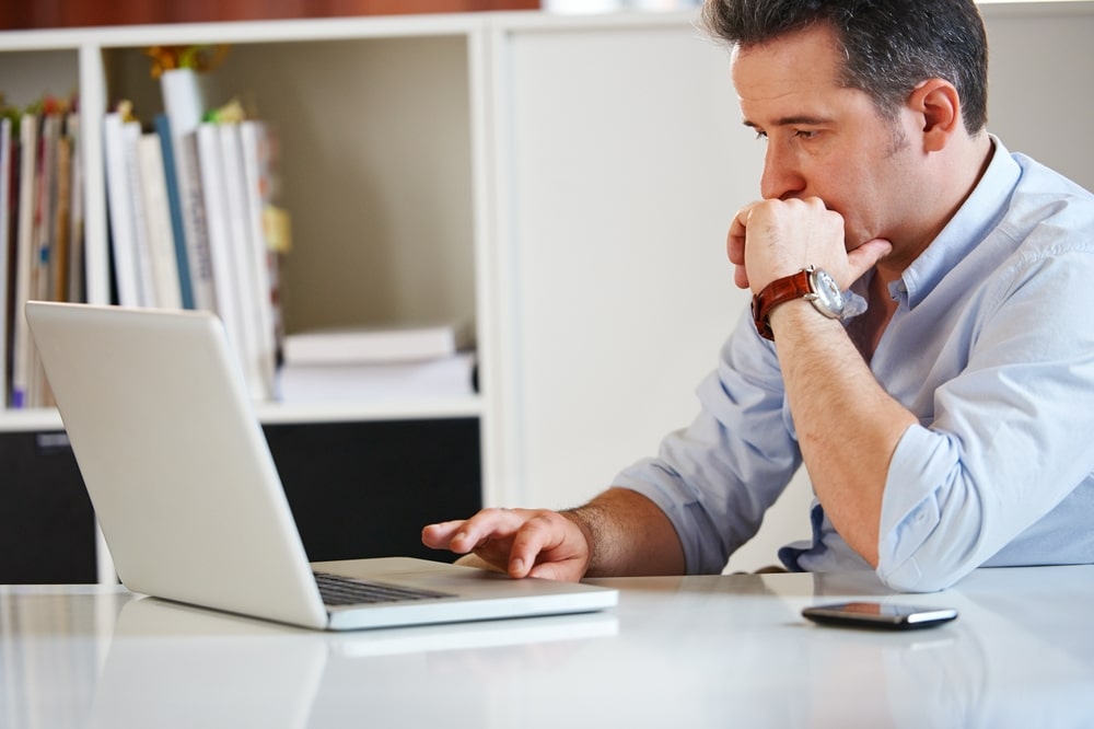 A man researching Dave Ramsey’s bankruptcy story on a laptop