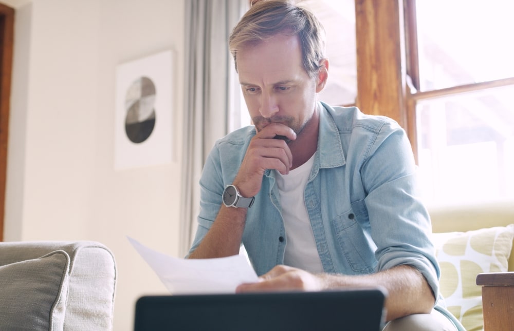 Man reviewing bankruptcy documents at home while considering if he can file without his spouse