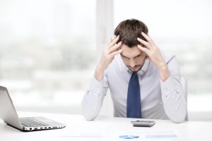 A stressed man is reviewing financial documents while considering how to file for bankruptcy