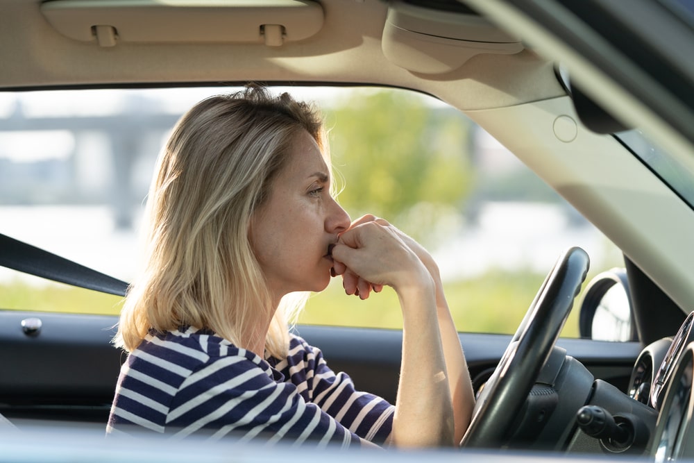 Worried woman sitting in her car with a thoughtful expression