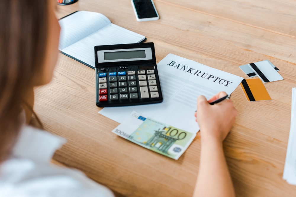 Person calculating finances with bankruptcy paperwork and credit cards on the desk