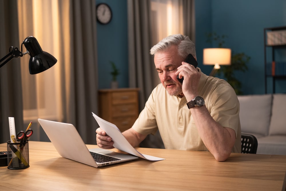 Older man discussing bankruptcy paperwork over the phone at home