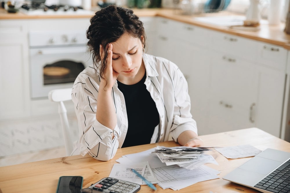 Stressed woman reviewing bills and paperwork at home while considering how many times she can file bankruptcy