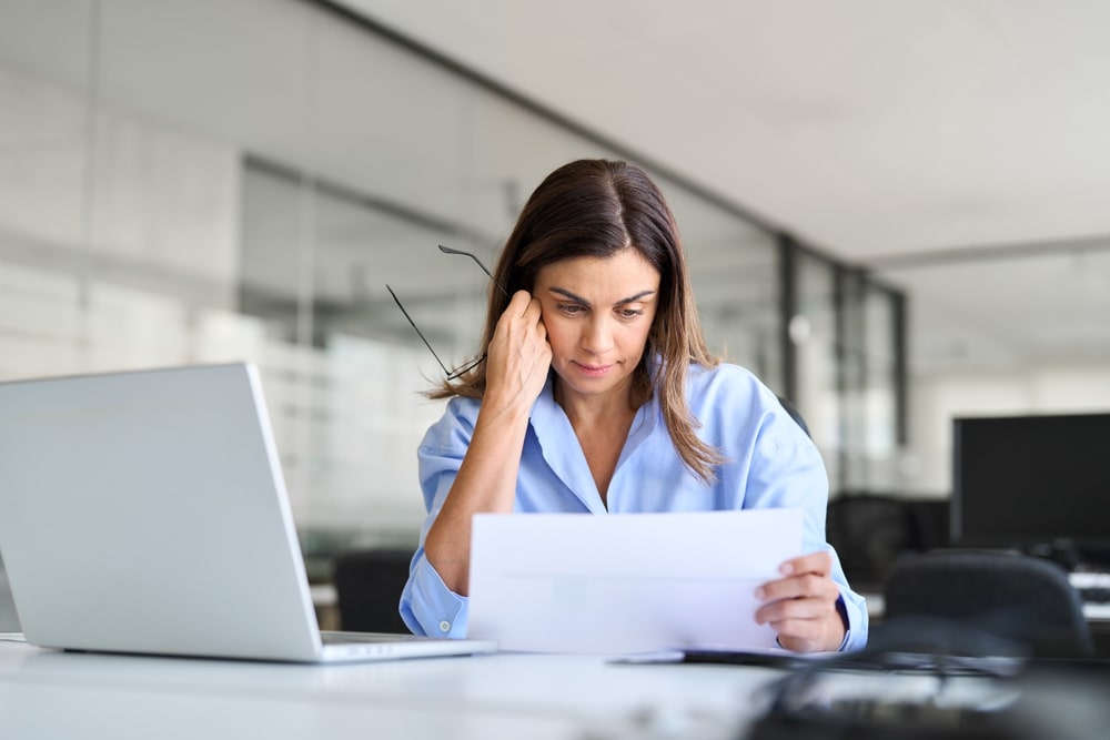 Concerned woman reading financial documents at her desk