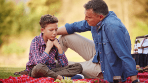 Father and son having serious conversation about child support obligations during family time outdoors
