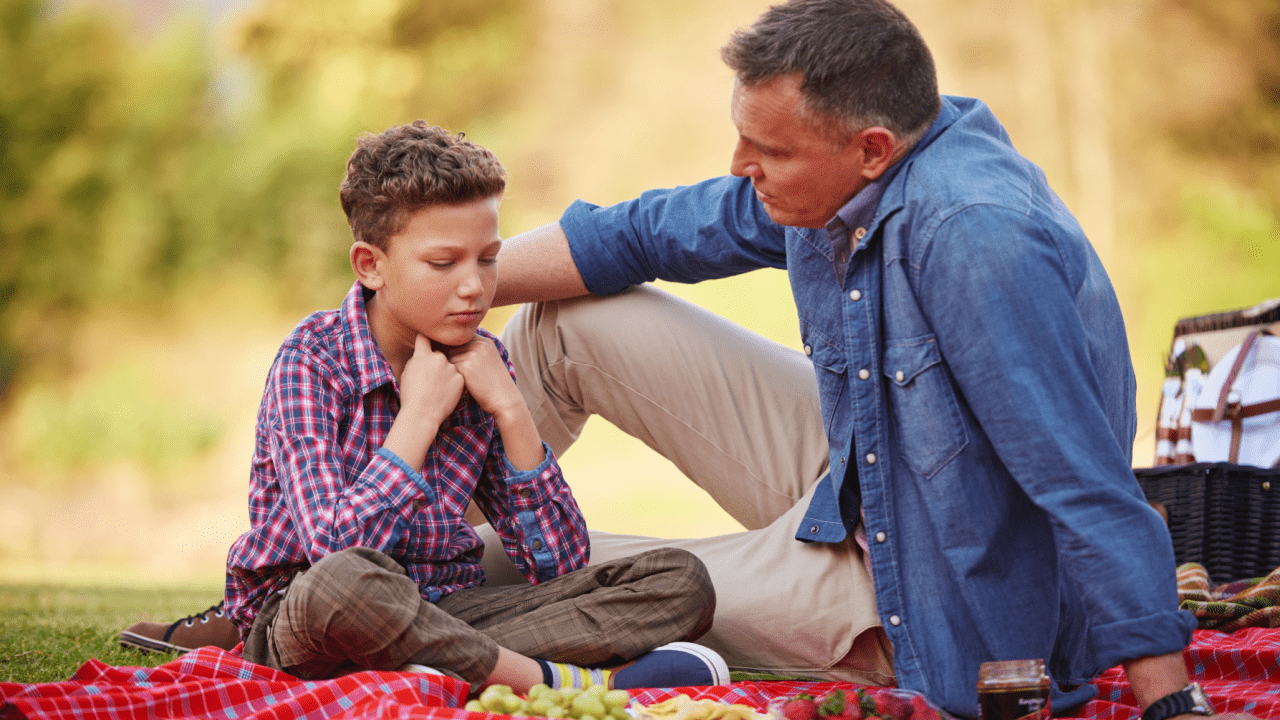 Father and son having serious conversation about child support obligations during family time outdoors