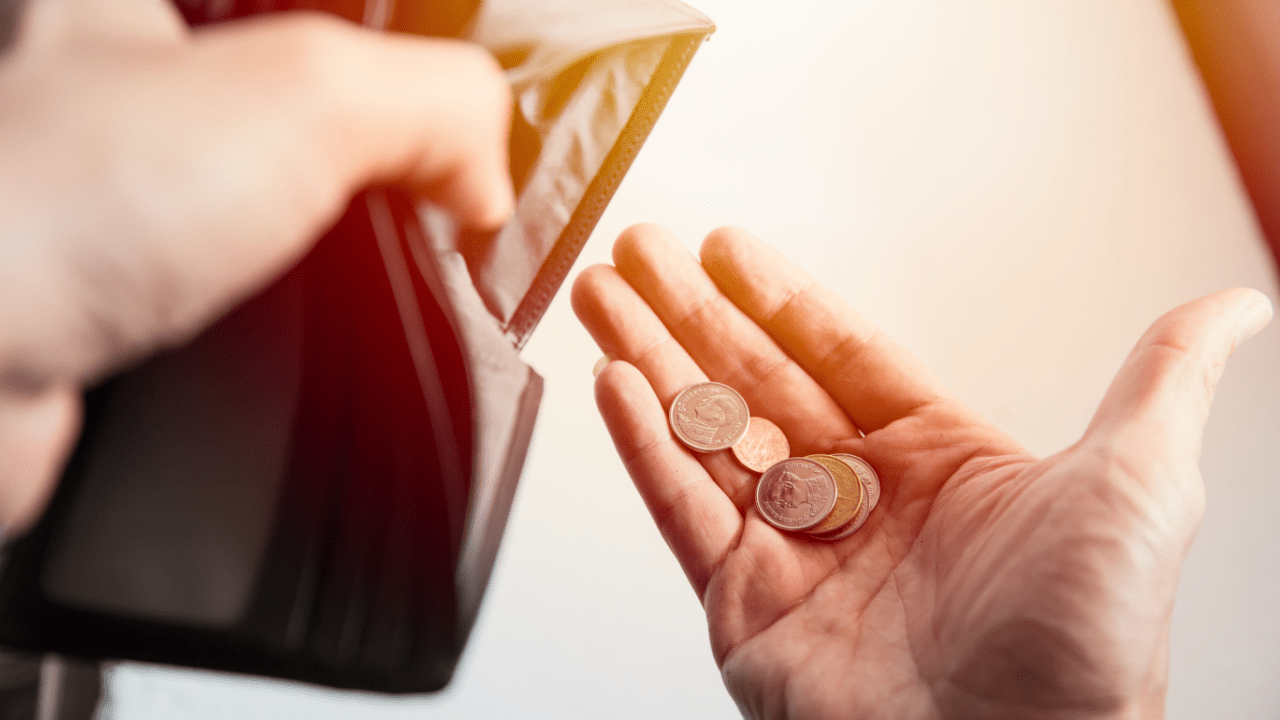 Person holding coins asking how do i file bankruptcy with no money while using laptop