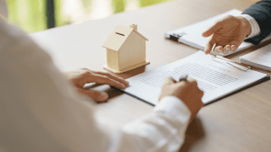Mortgage professionals reviewing loan documents explaining how long after you file bankruptcy can you buy a house with wooden house model on desk