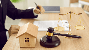 Wooden house model with gavel and scales of justice on lawyer desk showing what happens to your house when you file bankruptcy