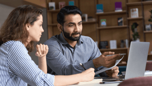 Two people discussing Chapter 7 bankruptcy lawyer fees while reviewing legal documents at a desk