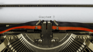 Vintage typewriter typing Chapter 7 on white paper showing bankruptcy documentation process