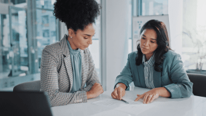 Two professional women discussing how long does Chapter 7 take during bankruptcy consultation meeting