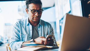 Man with phone and laptop researching do you lose your car if you file bankruptcy