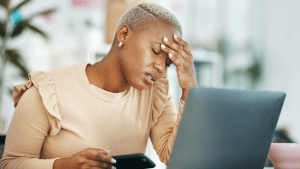Worried woman with phone and laptop wondering what happens to my house if i file bankruptcy