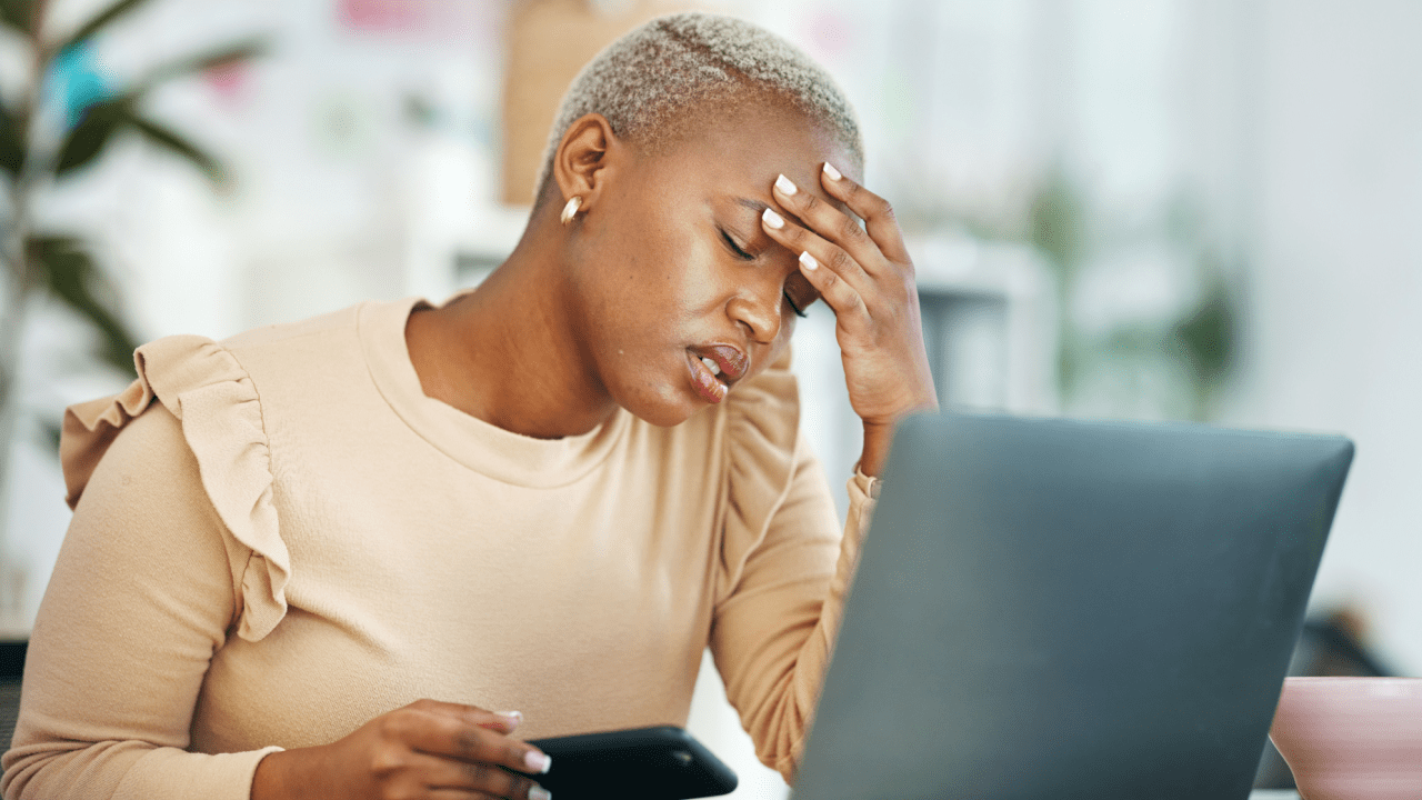 Worried woman with phone and laptop wondering what happens to my house if i file bankruptcy