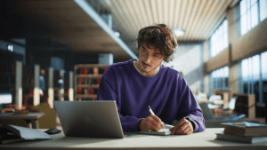 Young man with headphones researching how often can you file chapter 13 bankruptcy at library