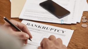 Person reviewing types of bankruptcy filing documents and forms on wooden desk