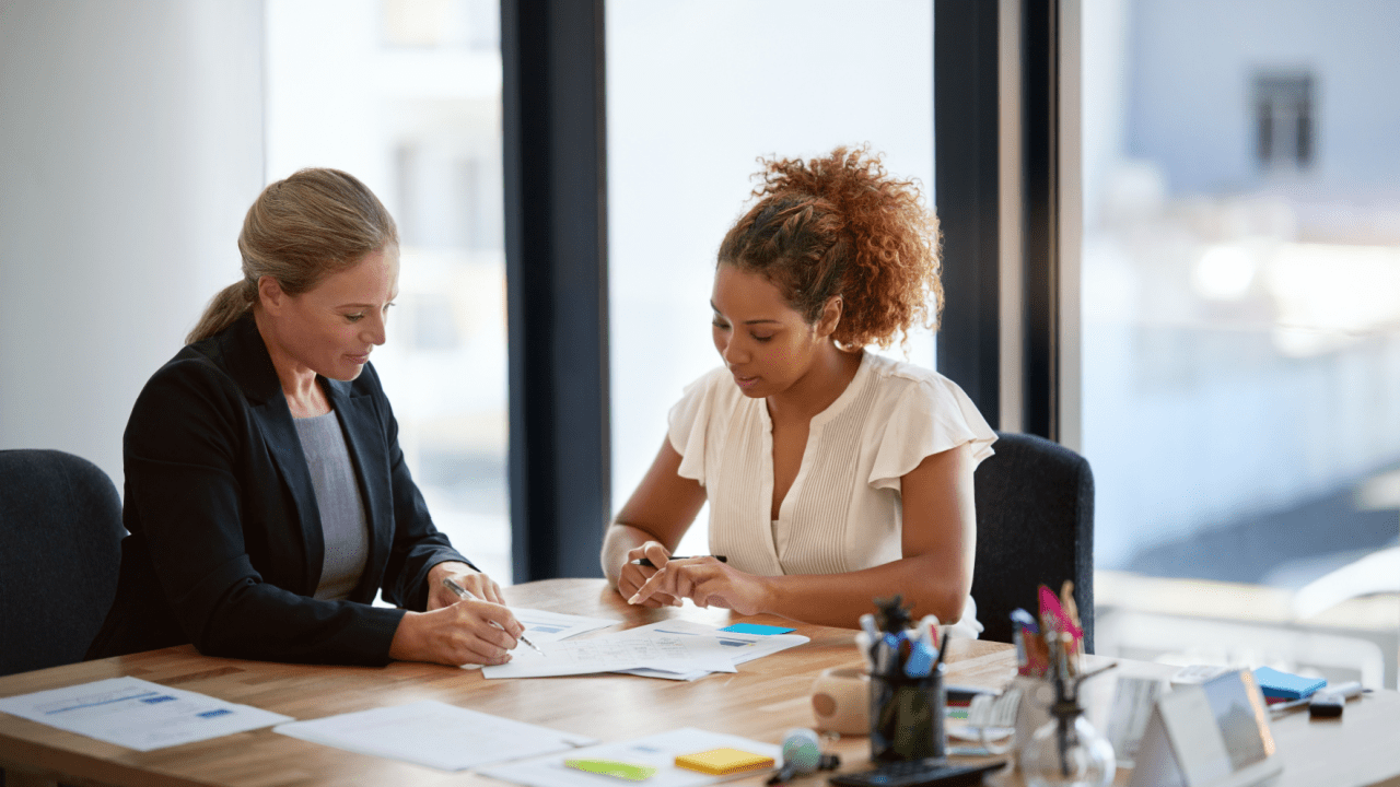 Two women discussing what to do before filing Chapter 7 bankruptcy with financial documents on desk