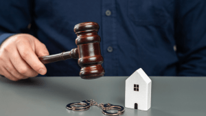 Judge's gavel over house model and handcuffs representing bankruptcy assets and property liquidation