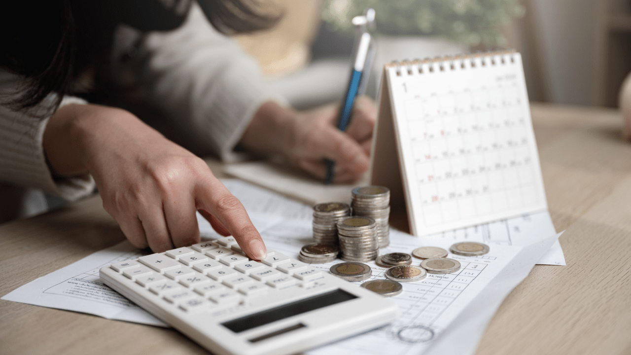 Person calculating what debts are not dischargeable in bankruptcy with calculator and financial documents