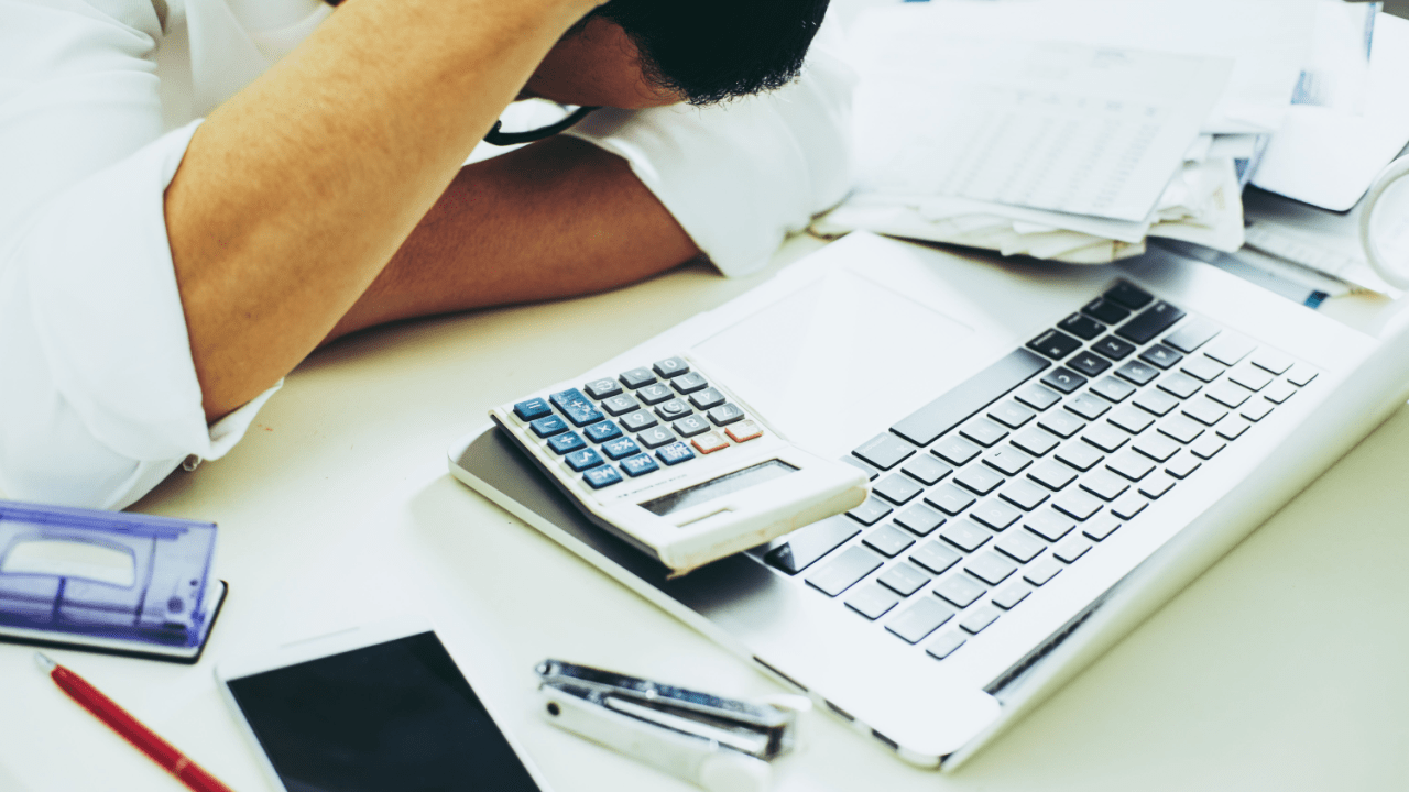 Person calculating which debts cannot be erased by bankruptcy at desk with laptop and financial documents
