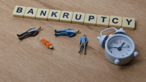 What type of bankruptcy clears all debt concept showing bankruptcy letter tiles with business figures and clock representing time-sensitive debt relief decisions