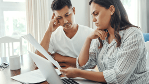 Stressed couple reviewing financial documents to understand which debts are not cleared by bankruptcy before filing for debt relief