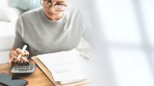 Woman calculating if she can file bankruptcy with $5000 debt using calculator and bills