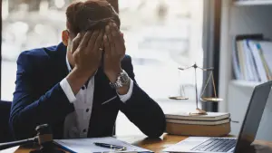 Stressed professional considering does Chapter 13 wipe out all debt while reviewing bankruptcy documents at desk