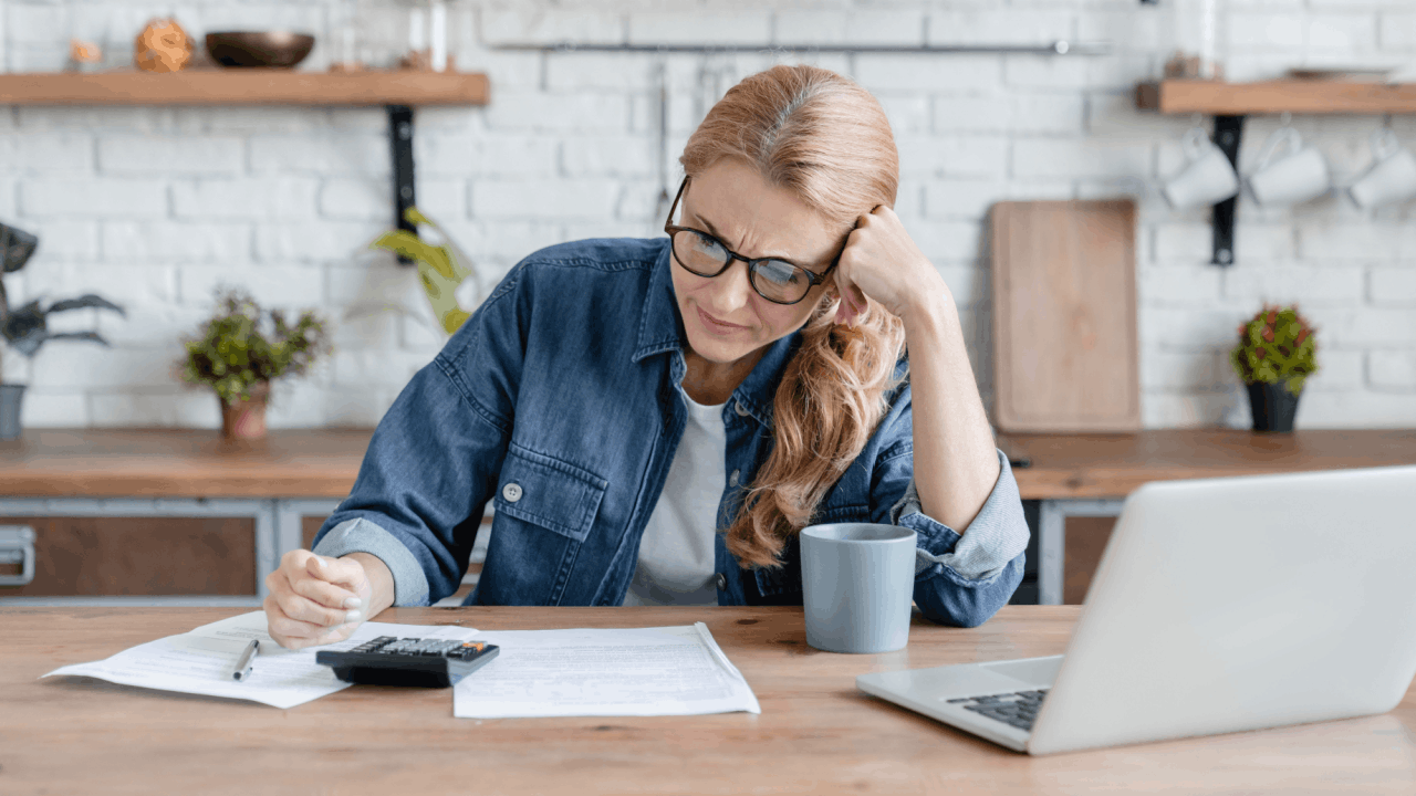 Woman reviewing what can't you do while in Chapter 13 bankruptcy documents at home with calculator and laptop
