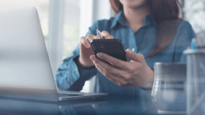 Person checking phone to learn what happens after filing Chapter 13 bankruptcy with laptop nearby