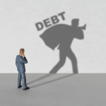What debts cannot be forgiven concept with businessman figurine casting shadow carrying heavy DEBT burden on gray background