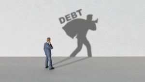What debts cannot be forgiven concept with businessman figurine casting shadow carrying heavy DEBT burden on gray background