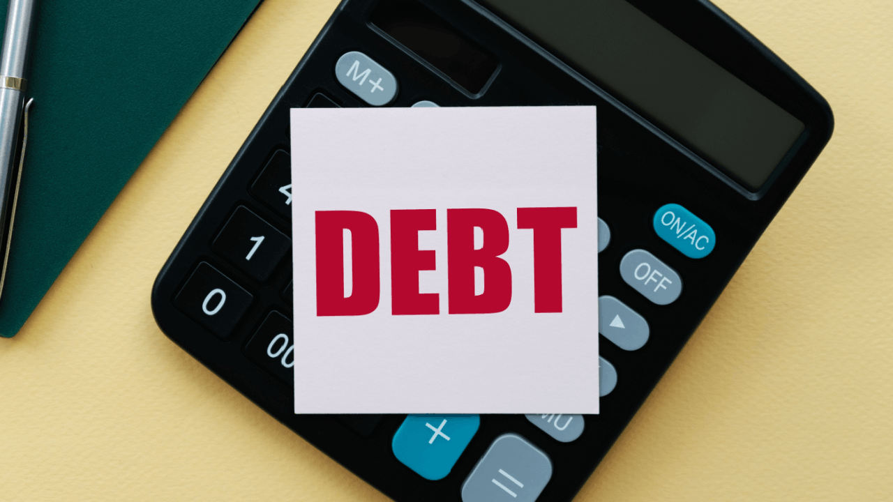 What debt cannot be erased concept with DEBT card on calculator beside pen and notebook on yellow desk