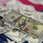 US hundred dollar bills spread across an American flag