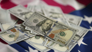 US hundred dollar bills spread across an American flag