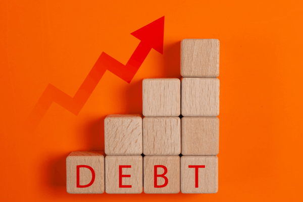 Does Chapter 11 forgive debt — wooden blocks spelling DEBT with rising arrow graph on orange background