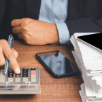 How much debt is too much — businessman calculating finances with a stack of documents on desk