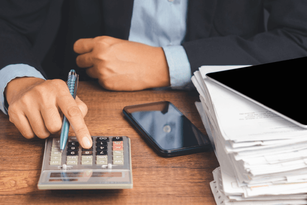 How much debt is too much — businessman calculating finances with a stack of documents on desk