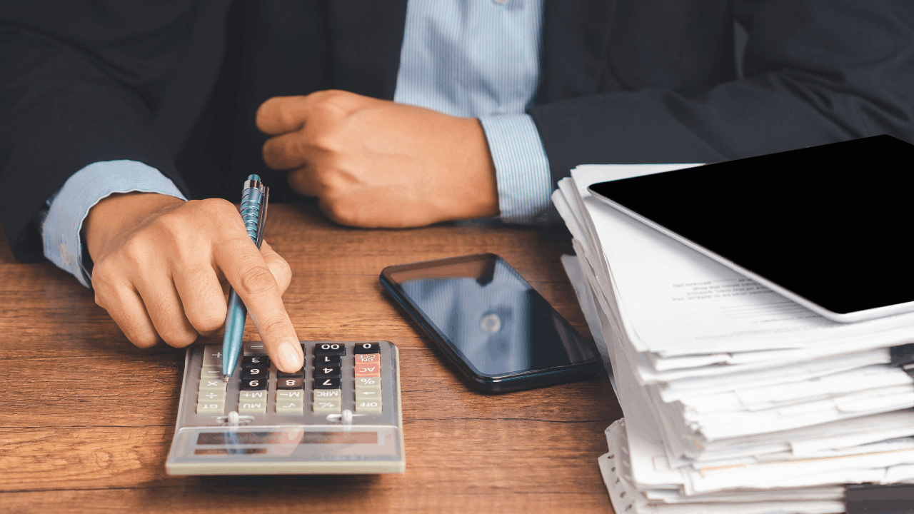 How much debt is too much — businessman calculating finances with a stack of documents on desk