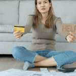 Woman holding credit card and HELP sign surrounded by bills