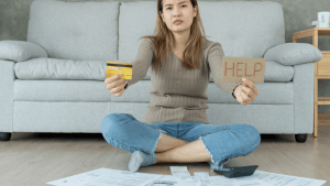 Woman holding credit card and HELP sign surrounded by bills